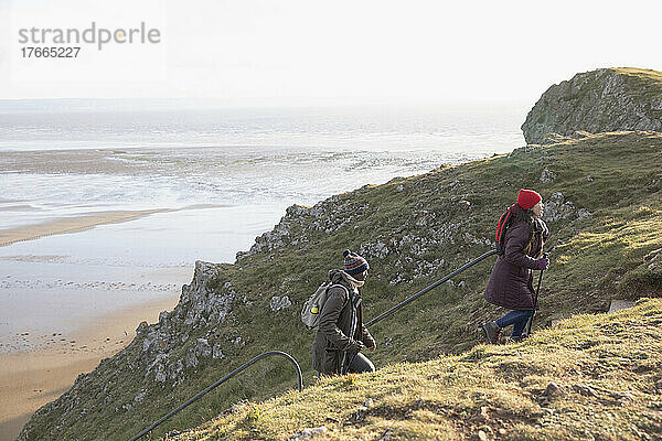 Wandererpaar klettert auf einer Klippe oberhalb des Meeresstrandes