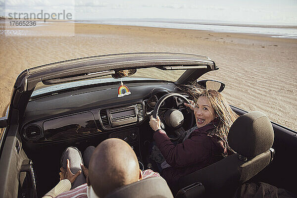 Portrait glückliches Paar im Cabrio am sonnigen Strand