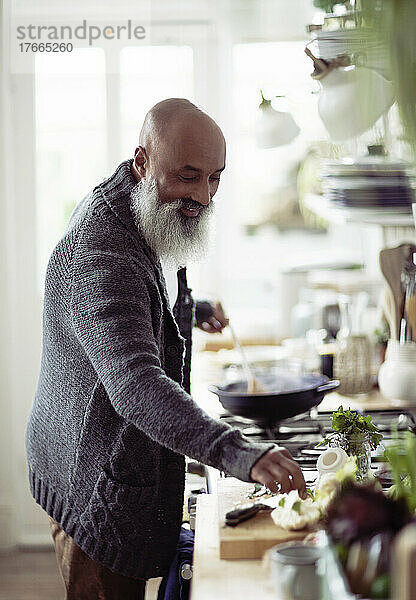 Lächelnder Mann mit Bart beim Kochen in der Küche