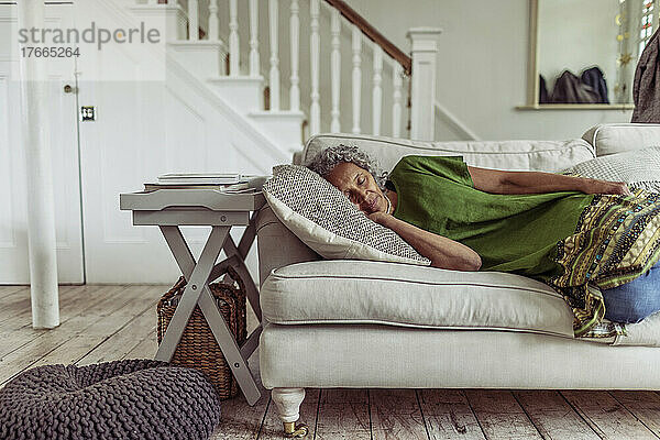 Gelassene ältere Frau schläft auf dem Wohnzimmersofa