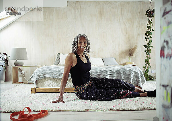 Porträt einer selbstbewussten älteren Frau  die sich auf dem Boden eines Schlafzimmers streckt