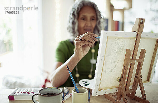 Ältere Frau malt an kleiner Staffelei