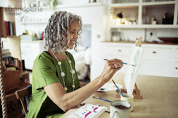 Glückliche ältere Frau malt an der Staffelei