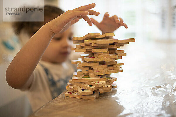 Mädchen stapelt Holz-Puzzleteile