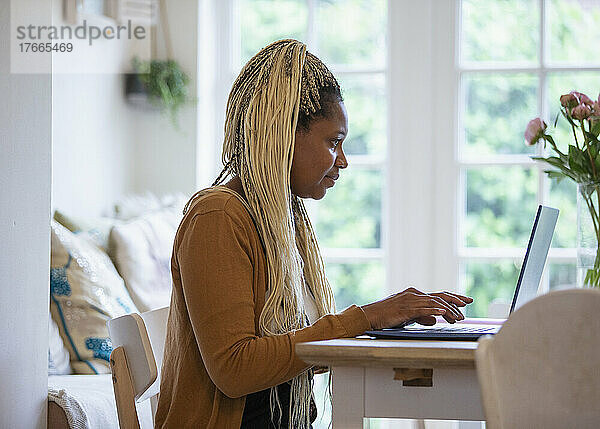 Frau mit blonden Zöpfen arbeitet von zu Hause aus am Laptop