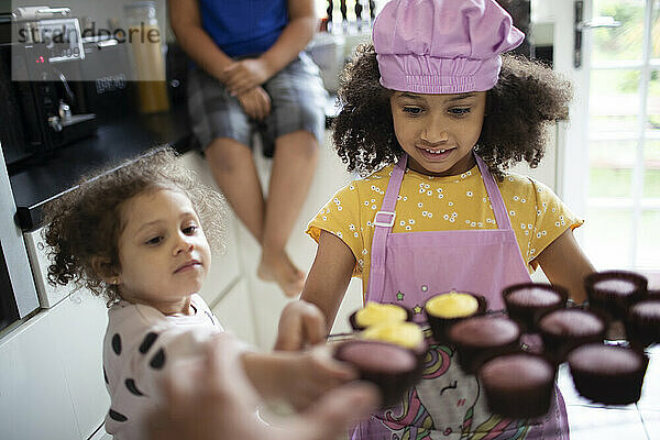 Süße Mädchen backen Cupcakes in der Küche