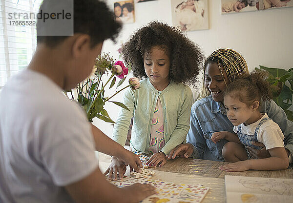 Mutter und Kinder bauen Puzzle am Tisch zusammen