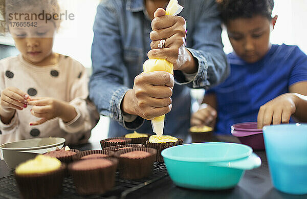 Mutter und Kinder beim Verzieren von Cupcakes