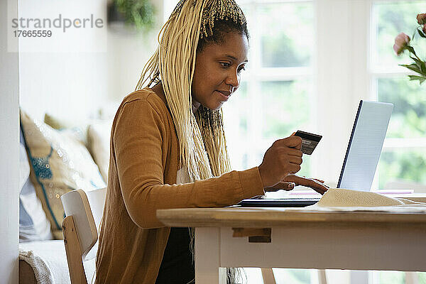 Frau mit Kreditkarte beim Online-Shopping am Laptop