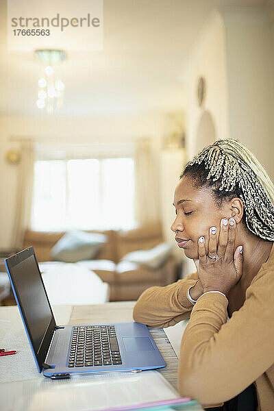 Müde Frau  die von zu Hause aus am Laptop arbeitet