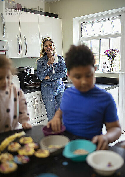 Mutter beobachtet Kinder beim Backen in der Küche