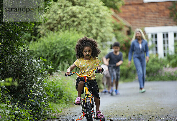 Mädchen fährt Fahrrad in der Einfahrt