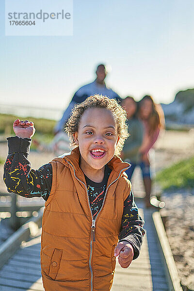 Porträt eines glücklichen  süßen Jungen mit Down-Syndrom  der auf dem Strandweg lächelt