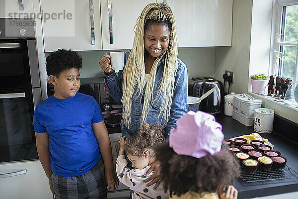 Glückliche Mutter und Kinder backen Cupcakes in der Küche
