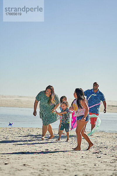 Glückliche Familie  die am sonnigen Strand spielt