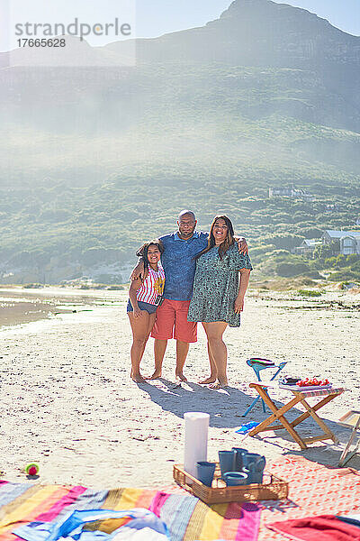 Porträt glücklicher Eltern und Tochter am sonnigen Strand