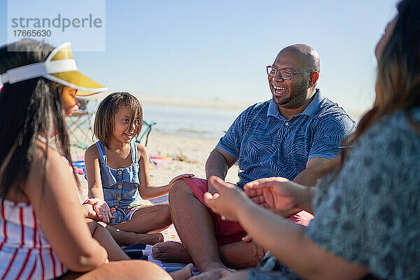 Glückliche Familie sitzt im Kreis am Strand