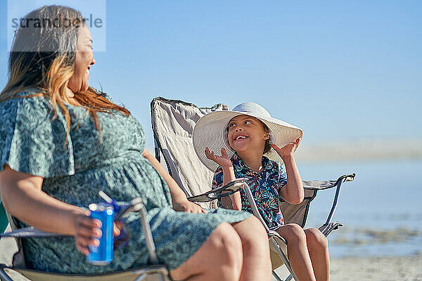 Mutter beobachtet glücklichen süßen Sohn mit Down-Syndrom mit Hut am Strand