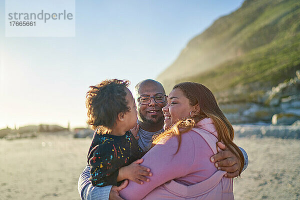 Glückliche Eltern und Sohn umarmen sich am sonnigen Strand