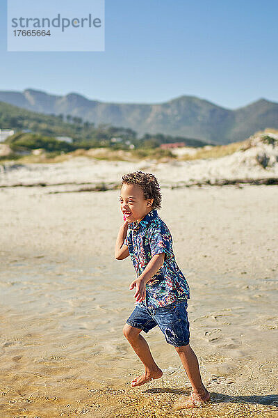 Glücklicher Junge mit Down-Syndrom  der am sonnigen Strand spielt