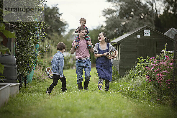 Glückliche Familie spaziert im Gras im Hinterhofgarten