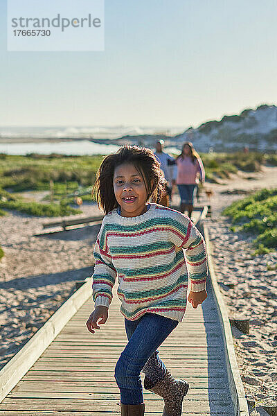 Sorgloses Mädchen läuft auf der sonnigen Strandpromenade