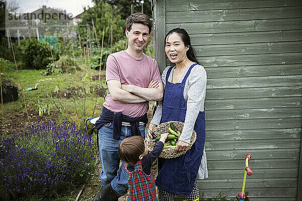 Porträt einer glücklichen Familie mit geerntetem Gemüse im Garten