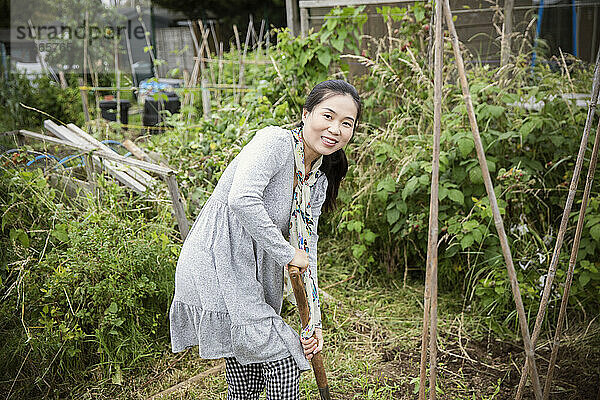 Porträt einer glücklichen Frau  die im Gemüsegarten gärtnert