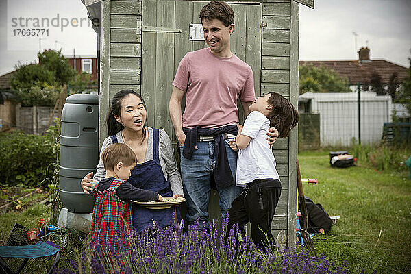Glückliche Familie lacht über Gartenschuppen