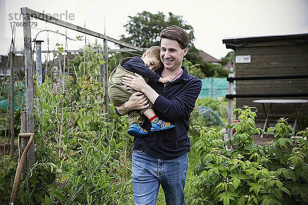 Glücklicher Vater hält seinen kleinen Sohn im Garten