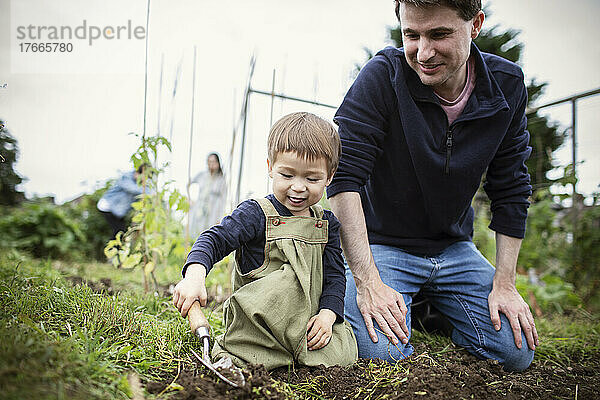 Vater und Sohn graben mit der Kelle im Gartenboden