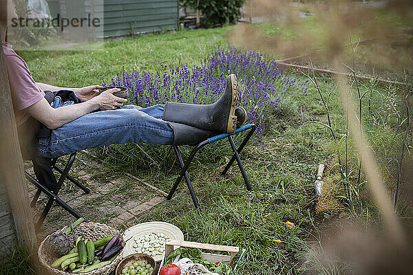 Mann entspannt sich im Garten mit geerntetem Gemüse