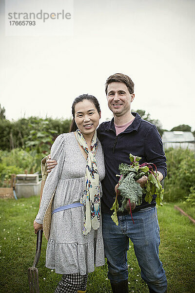 Porträt eines glücklichen Paares mit geernteten Rüben im Garten