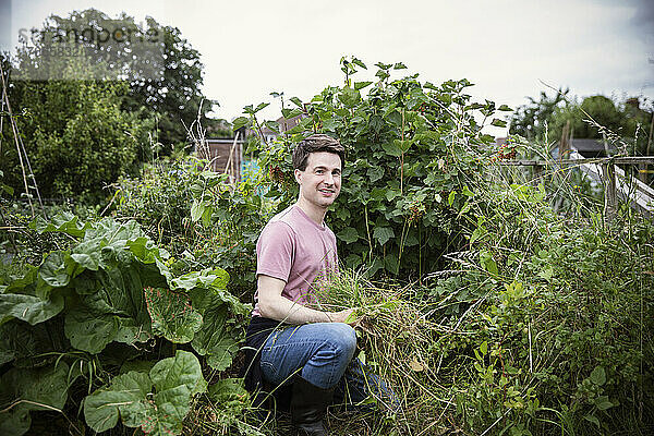 Porträt lächelnder Mann bei der Gartenarbeit im Hinterhofgarten