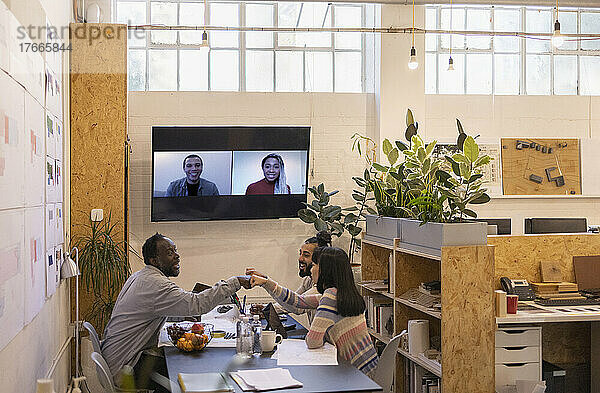 Geschäftsleute stoßen bei Videokonferenz-Bürobesprechung mit der Faust aufeinander