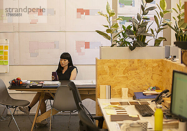 Architektin nutzt Smartphone im Büro