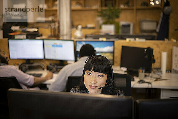 Porträt einer lächelnden Geschäftsfrau mit Headset  die im Büro arbeitet