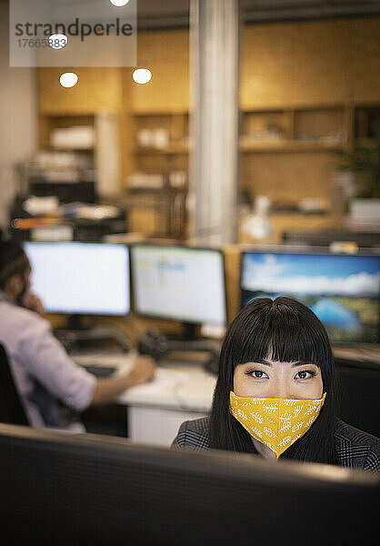 Porträt einer selbstbewussten Geschäftsfrau mit Gesichtsmaske am Computer im Büro