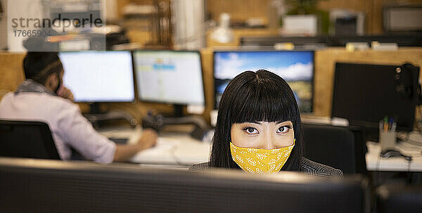 Porträt einer selbstbewussten Geschäftsfrau mit Gesichtsmaske  die im Büro arbeitet