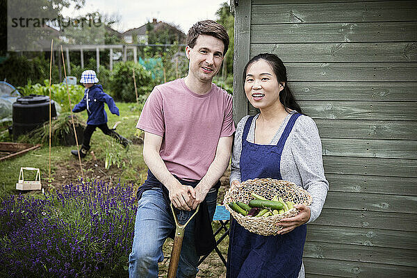 Porträt eines glücklichen Paares mit geerntetem Gemüse im Garten