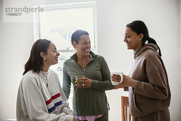 Glückliche Mutter und junge erwachsene Töchter trinken Tee und reden