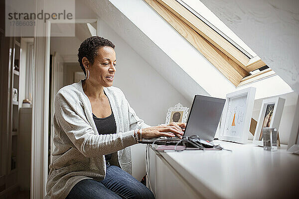Reife Frau  die von zu Hause aus am Laptop arbeitet