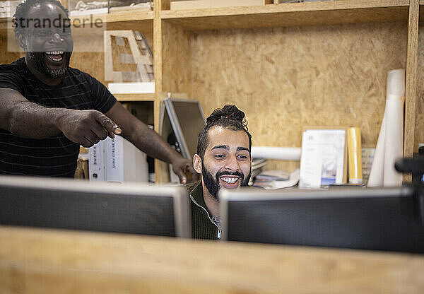 Lachende Geschäftsleute  die im Büro an Computern arbeiten
