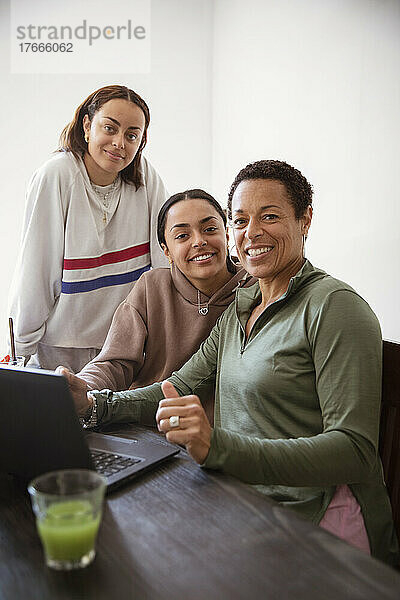 Porträt lächelnde Mutter und junge erwachsene Töchter mit Laptop