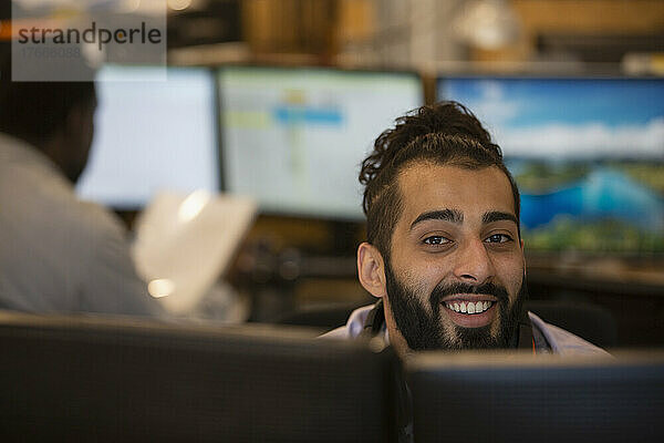 Porträt eines lächelnden jungen Geschäftsmannes  der im Büro arbeitet