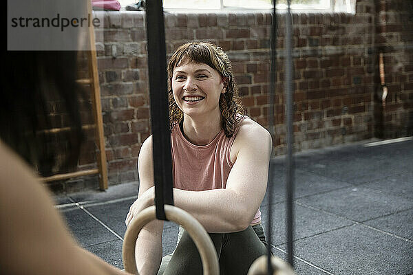 Lächelnde junge Frau trainiert mit einer Freundin im Fitnessstudio