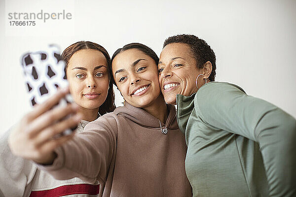 Glückliche Mutter und junge erwachsene Töchter machen Selfie mit Smartphone