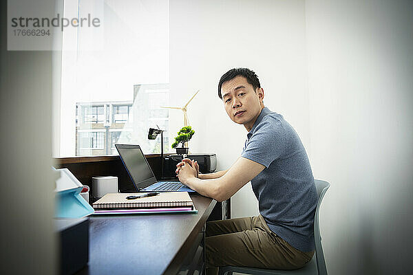 Porträt eines selbstbewussten männlichen Ingenieurs  der im Büro am Laptop arbeitet