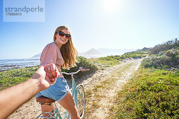 POV glückliche Freundin auf dem Fahrrad auf sonnigem Sommerstrandweg