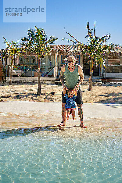 Vater und süßer kleiner Sohn spielen im sonnigen Sommermeer